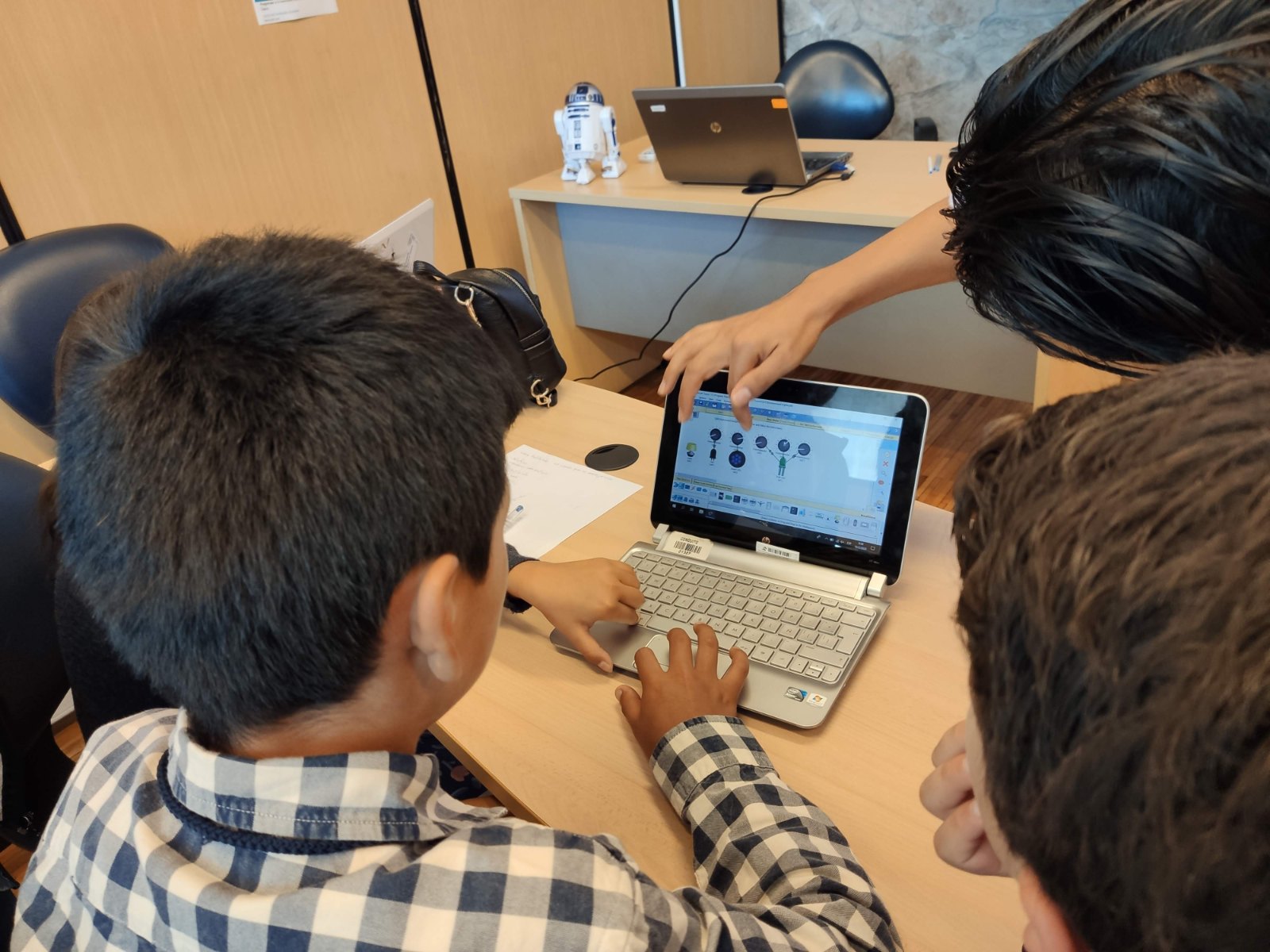 Facilitador acompañando a estudiantes frente a un computador en un taller de la Fundación REBDI